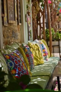 Vibrant outdoor cafe seating with colorful patterned cushions in a sunny setting.