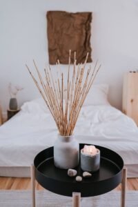 A minimalist bedroom featuring a candle, vase with sticks, and a cozy ambiance.