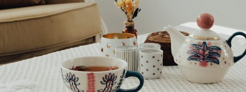 A charming indoor setup featuring a patterned porcelain teapot, matching cups, and vintage decor.