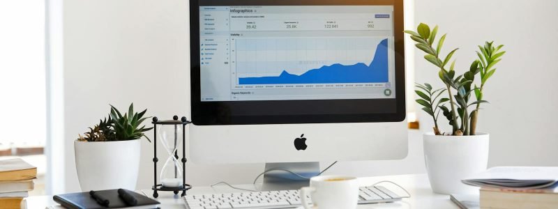 A clean, contemporary workspace featuring a desktop with analytics on the screen and plants for a fresh look.