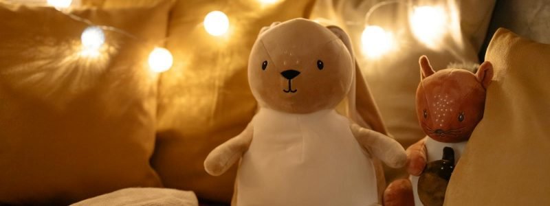 Warm and inviting bedroom scene with plush toys, pillows, and string lights creating a comforting ambiance.