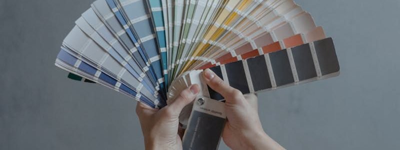 Hands displaying a fan of paint color swatches against a gray wall, ideal for home renovation projects.