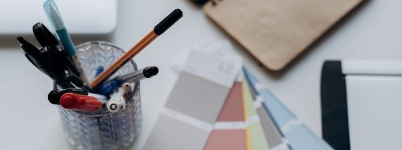 Organized workspace featuring color swatches, notebook, laptop, and stationery for design projects.