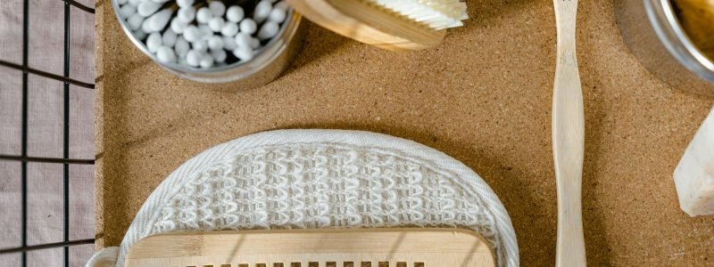 Eco-friendly wooden bathroom essentials including comb, toothbrush, and brush in a flat lay.