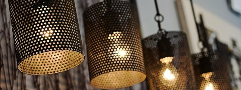 A row of modern perforated light fixtures hanging indoors, creating a cozy ambiance.